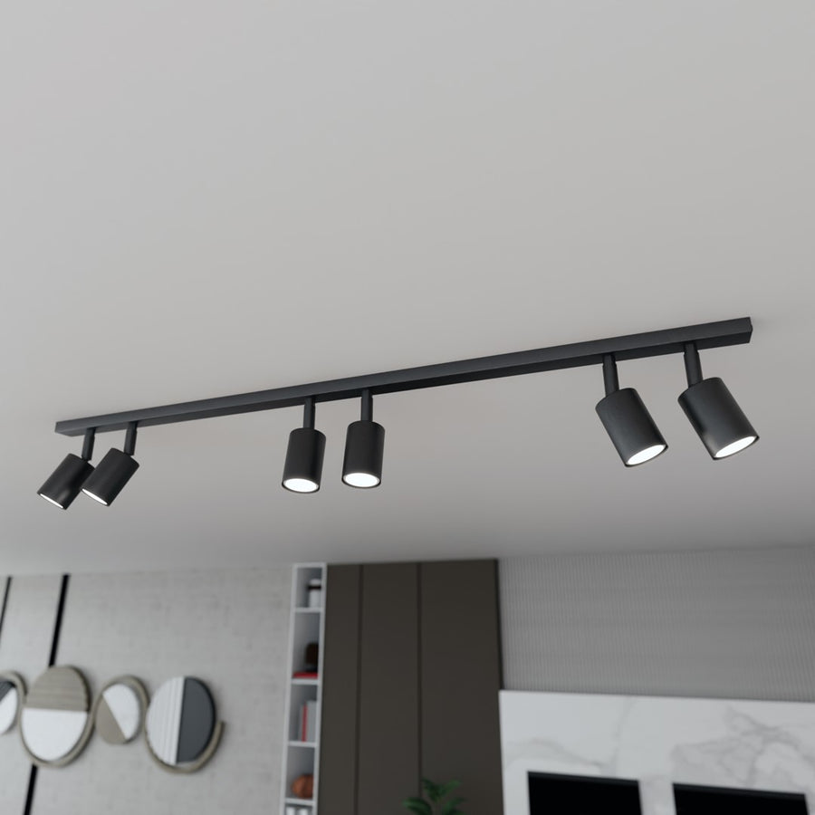 Vue en plongée du luminaire noir au plafond, au-dessus du salon et de la cuisine ouverte.