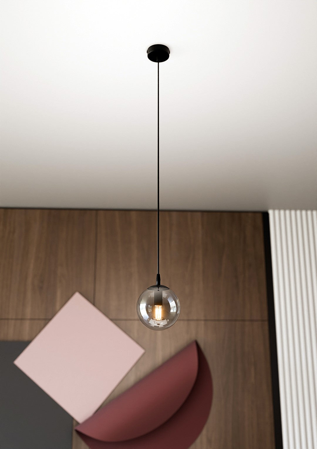 Suspension globe en verre fumé suspendue au-dessus d'une table en bois avec papiers colorés.