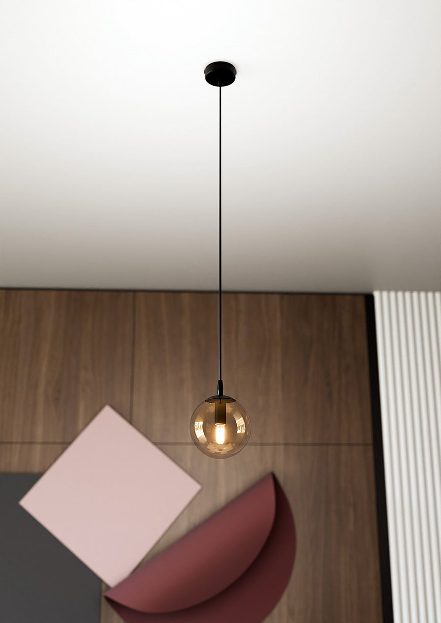 Suspension unique éclairée au-dessus d'un bureau en bois, composition graphique.