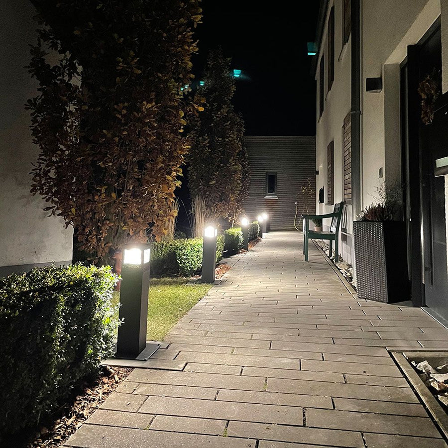Allée de jardin éclairée la nuit par des bornes basses alignées le long des haies
