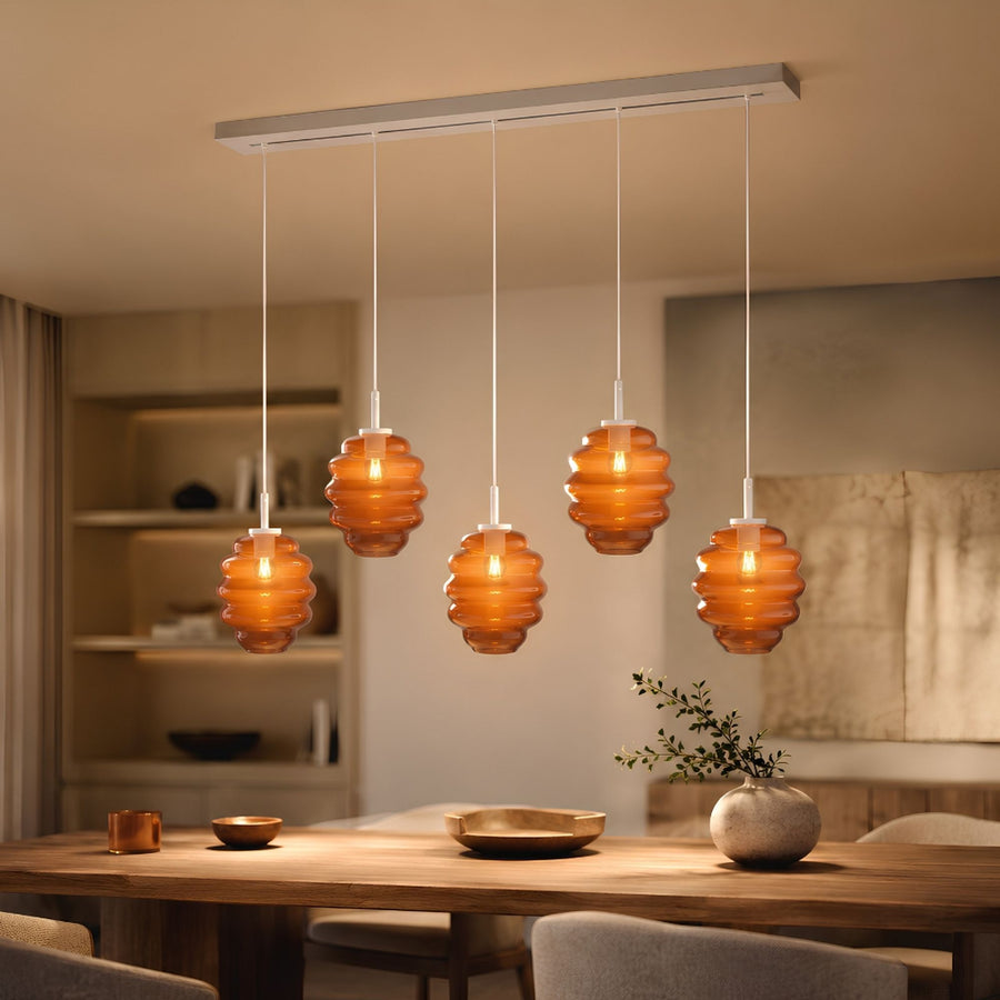Suspension cinq verres ambrés côtelés suspendus au-dessus d'une table en bois chaleureuse