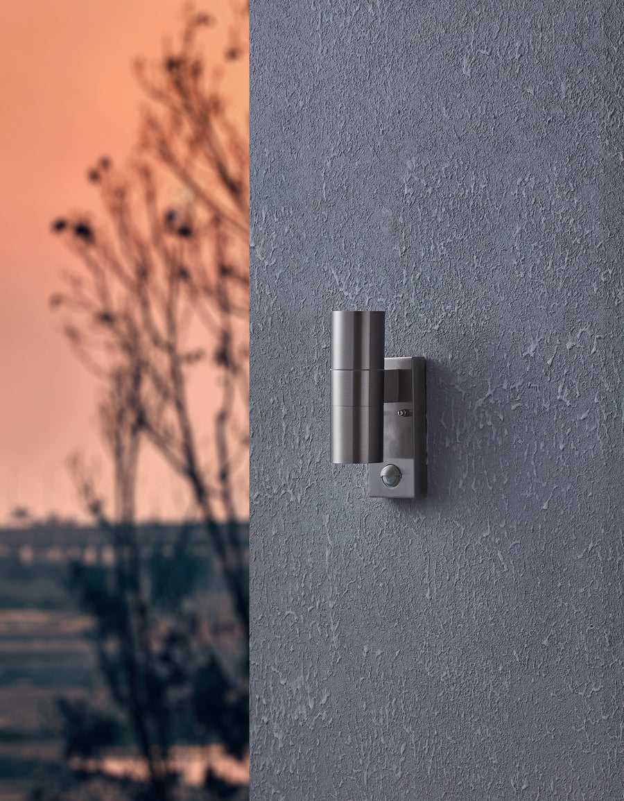 Vue en situation de l'applique murale éclairant un mur extérieur crépi au crépuscule.