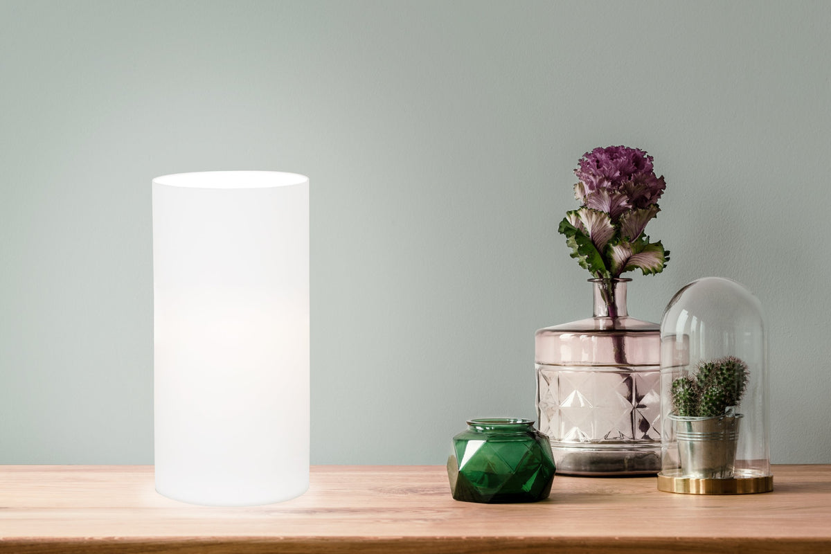 Mise en ambiance du luminaire allumé sur une table en bois, décor floral