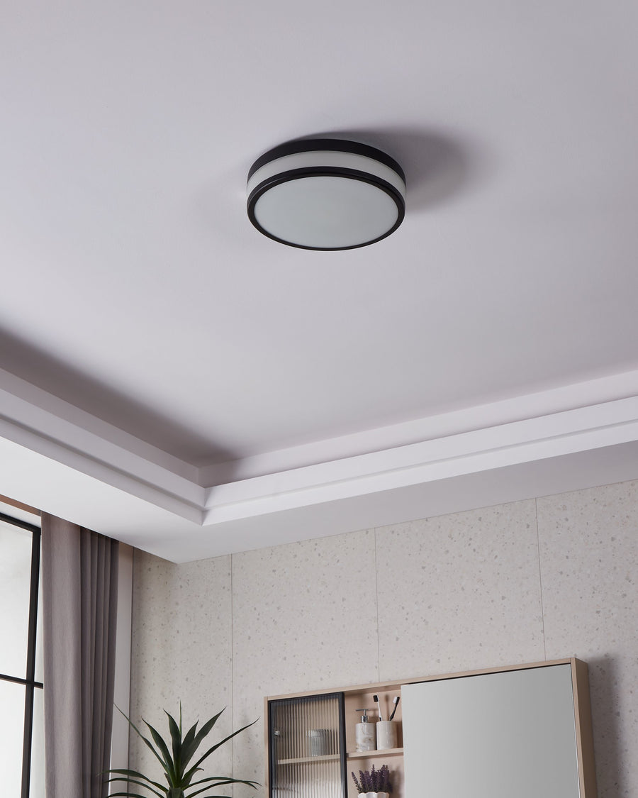 Plafonnier éteint fixé au plafond dans une pièce avec moulures et meuble.