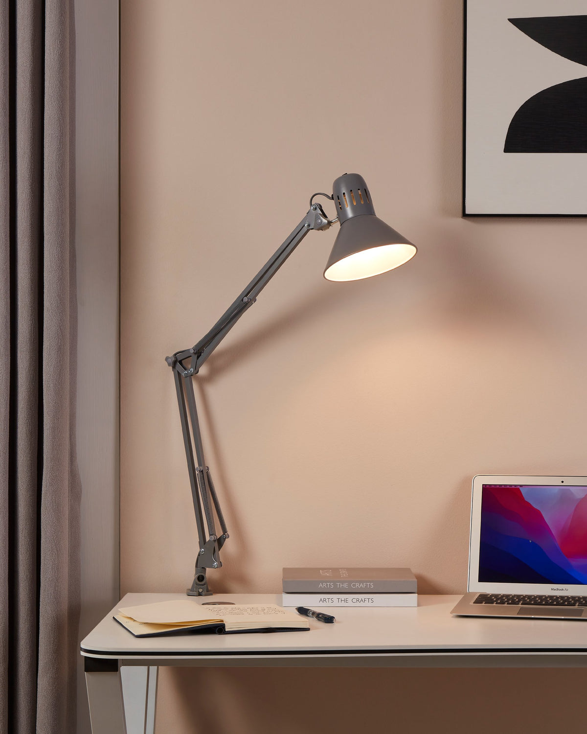 Lampe de bureau allumée, ambiance chaleureuse, éclairant un ordinateur portable et des carnets