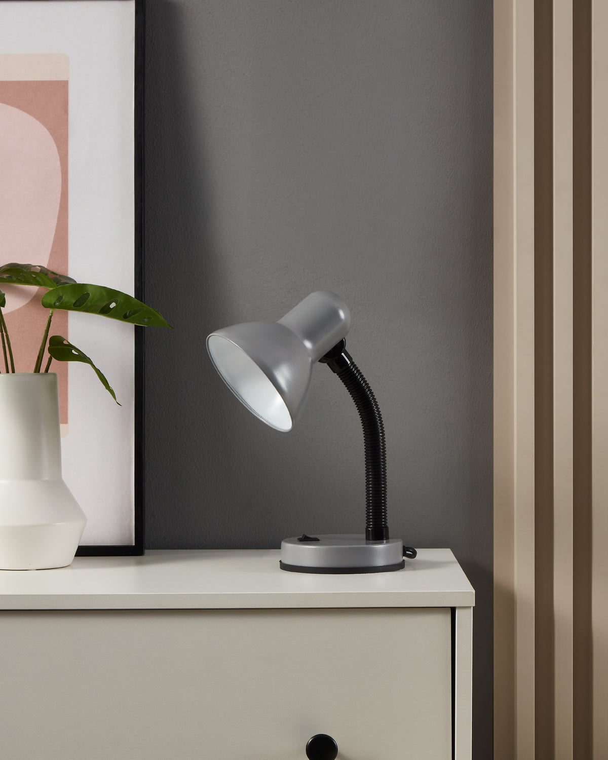 Mise en ambiance sur un meuble blanc, lampe allumée près d'une plante verte