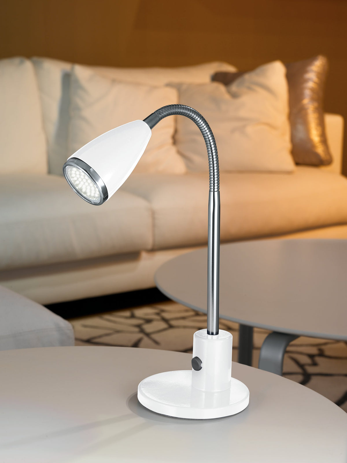 Lampe blanche posée sur une table basse devant un canapé beige en ambiance