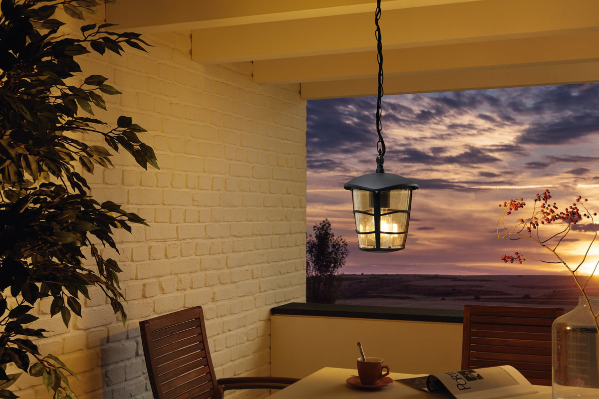 Mise en ambiance : lanterne allumée sous une pergola au coucher du soleil
