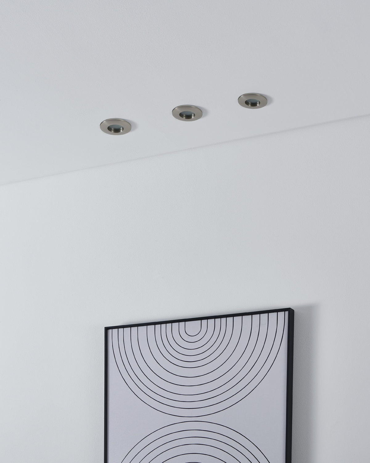 Trois spots encastrés au plafond blanc au-dessus d'un cadre graphique