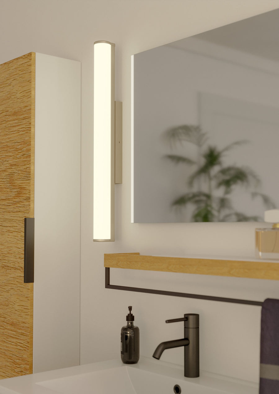 Luminaire installé verticalement au mur au-dessus d'un miroir de salle de bain moderne.