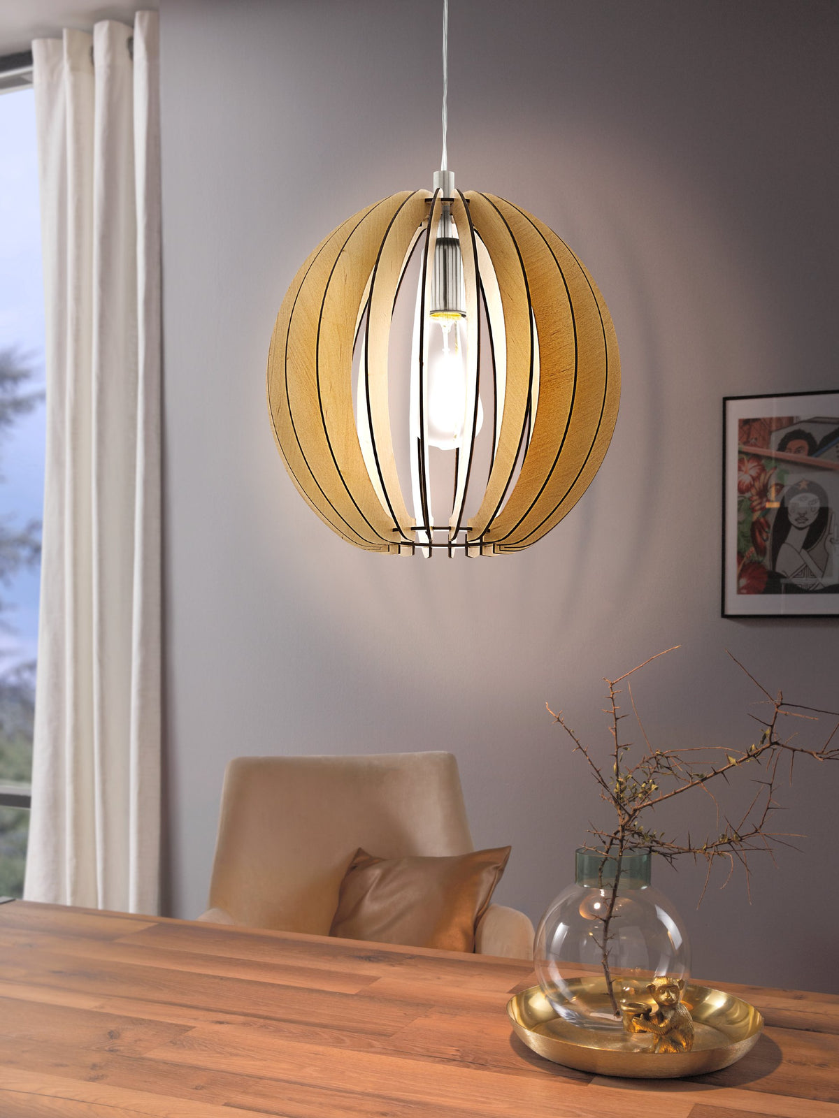 Gros plan du luminaire allumé au-dessus d'une table en bois, ampoule visible à l'intérieur.