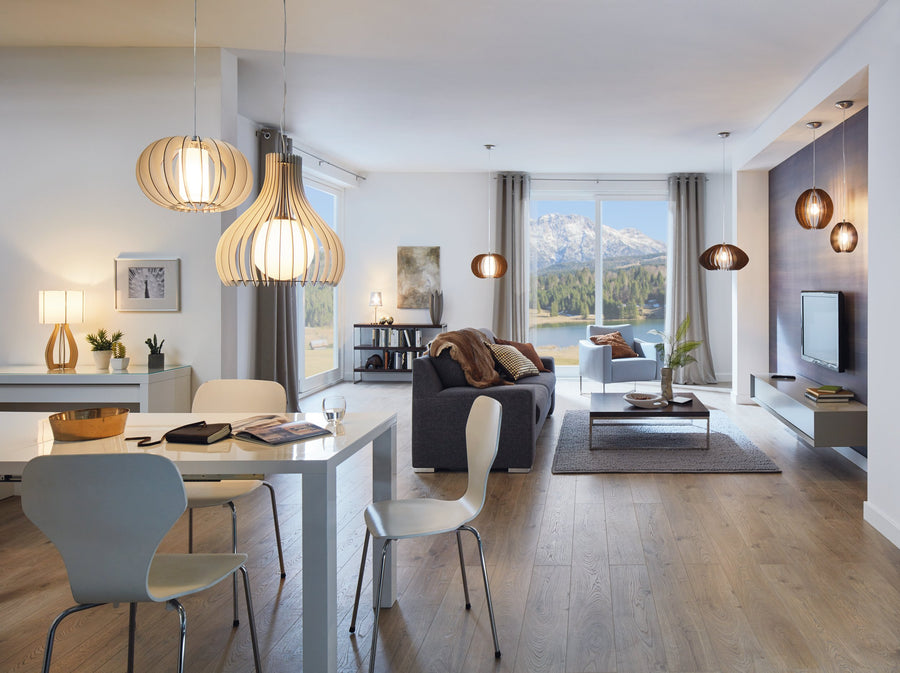 Ambiance salle à manger et salon, suspensions en bois allumées, vue sur la montagne.