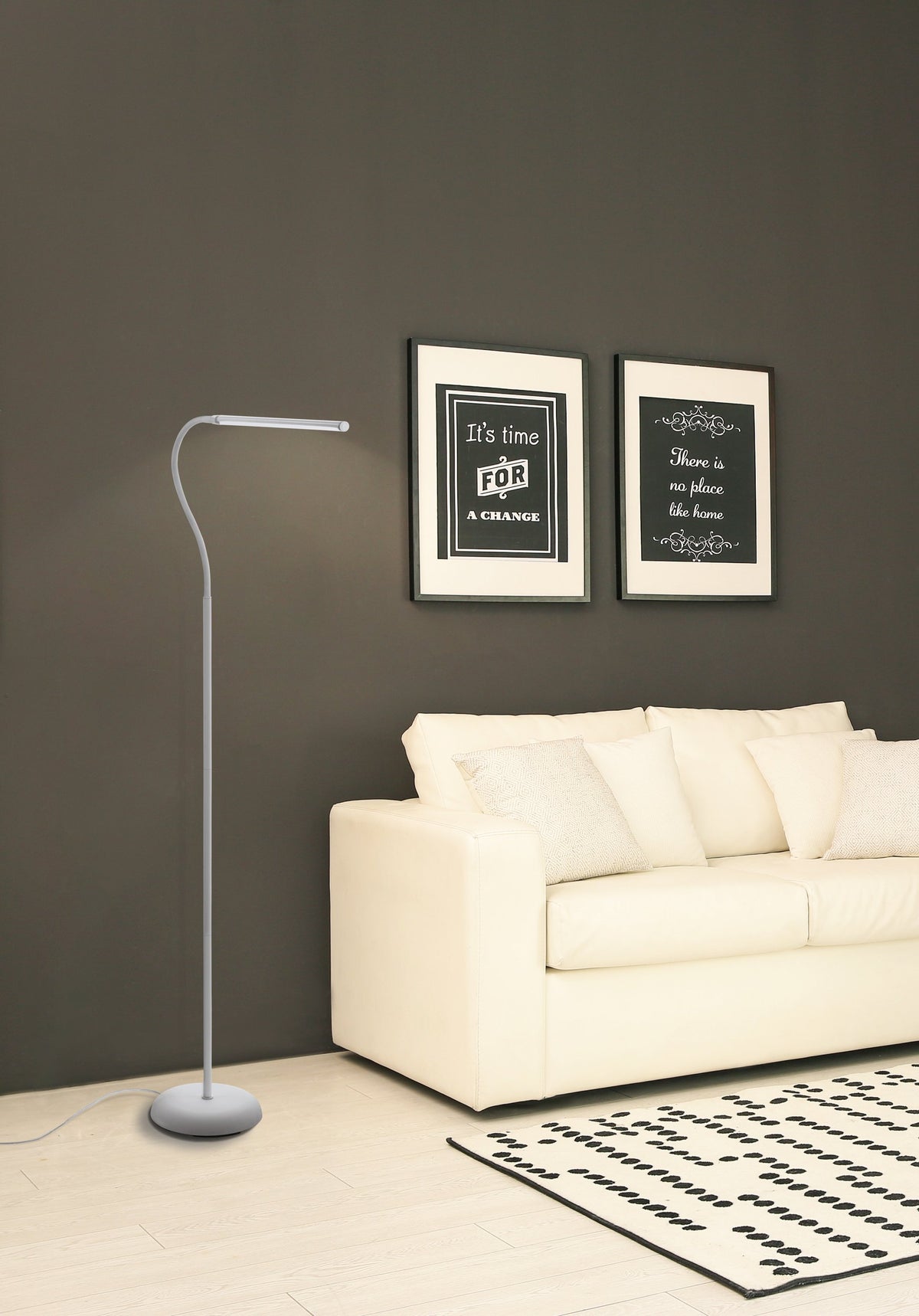Mise en ambiance salon sombre, lampadaire blanc devant un canapé beige