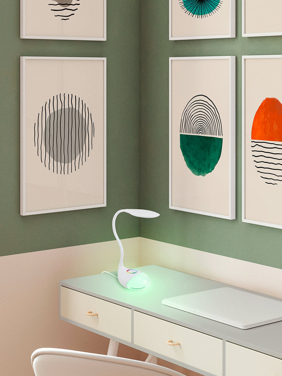 Lampe posée sur un bureau, éclairant la pièce d'une lumière verte, entourée de cadres muraux.