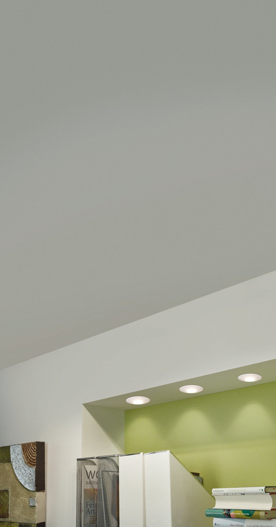Trois spots encastrés dans un plafond blanc éclairant un mur vert menthe
