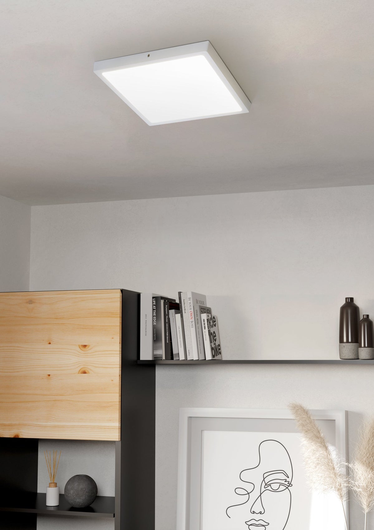 Mise en ambiance du luminaire allumé au plafond, au-dessus d'une étagère en bois clair