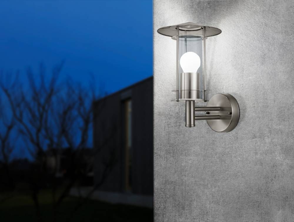 Mise en ambiance nocturne de l'applique fixée sur un mur gris devant une maison