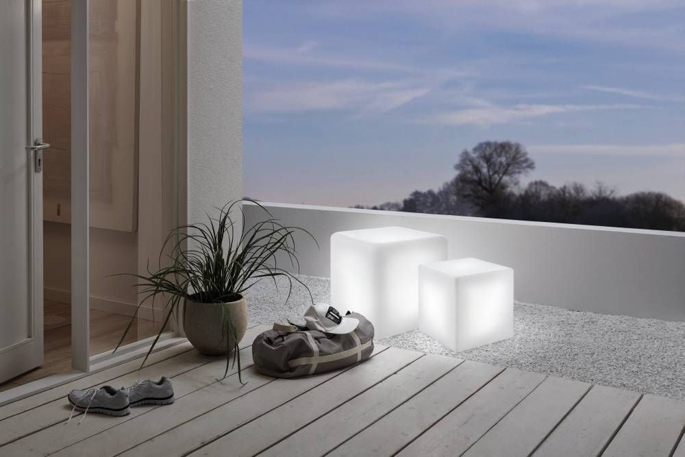 Mise en ambiance sur une terrasse, deux cubes lumineux allumés près d'un mur blanc