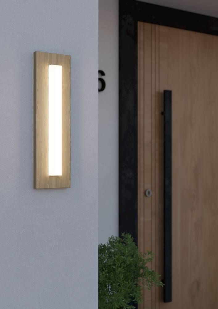 Applique extérieure allumée fixée sur un mur blanc près d'une porte en bois, mise en ambiance.