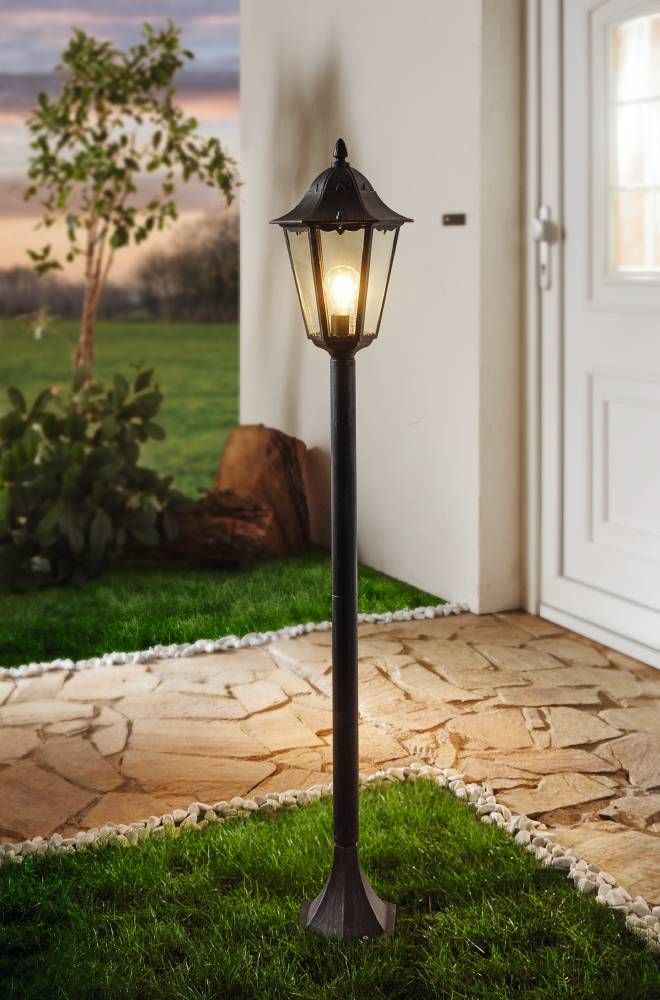 Mise en ambiance d'un lampadaire allumé devant une porte, terrasse en pierre