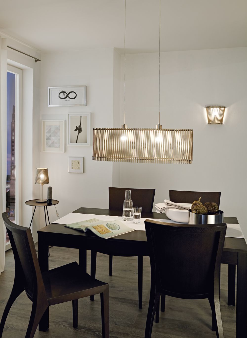 Mise en ambiance : luminaire suspendu au-dessus d'une table de salle à manger, éclairé.