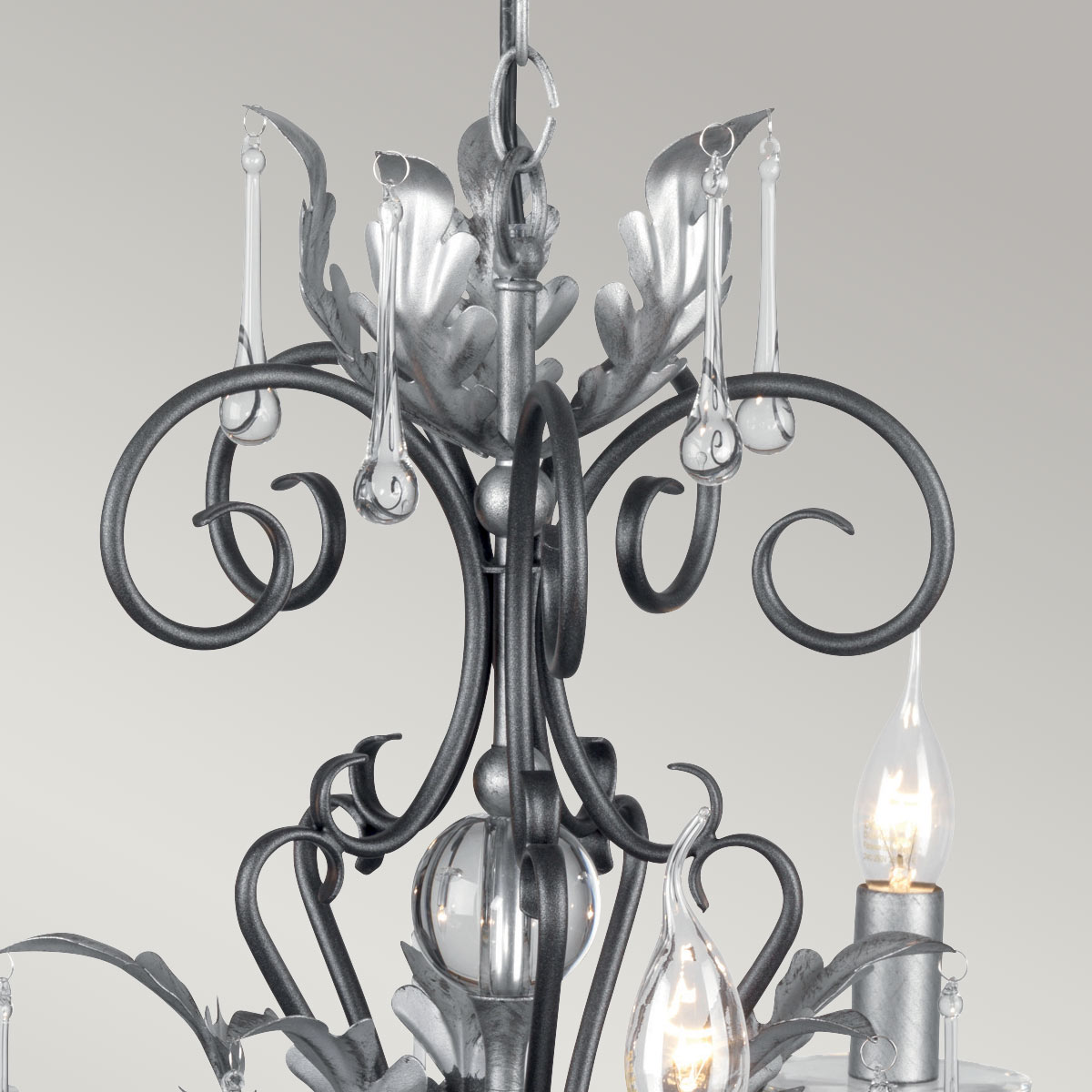 Détail du sommet : feuilles d'acanthe argentées, volutes noires et gouttes de verre