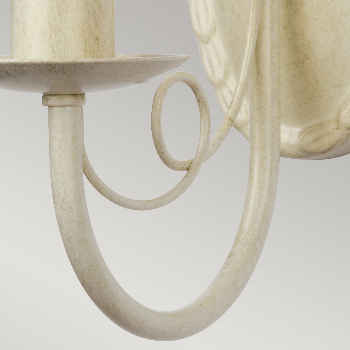 Détail du bras recourbé en métal crème avec boucle décorative