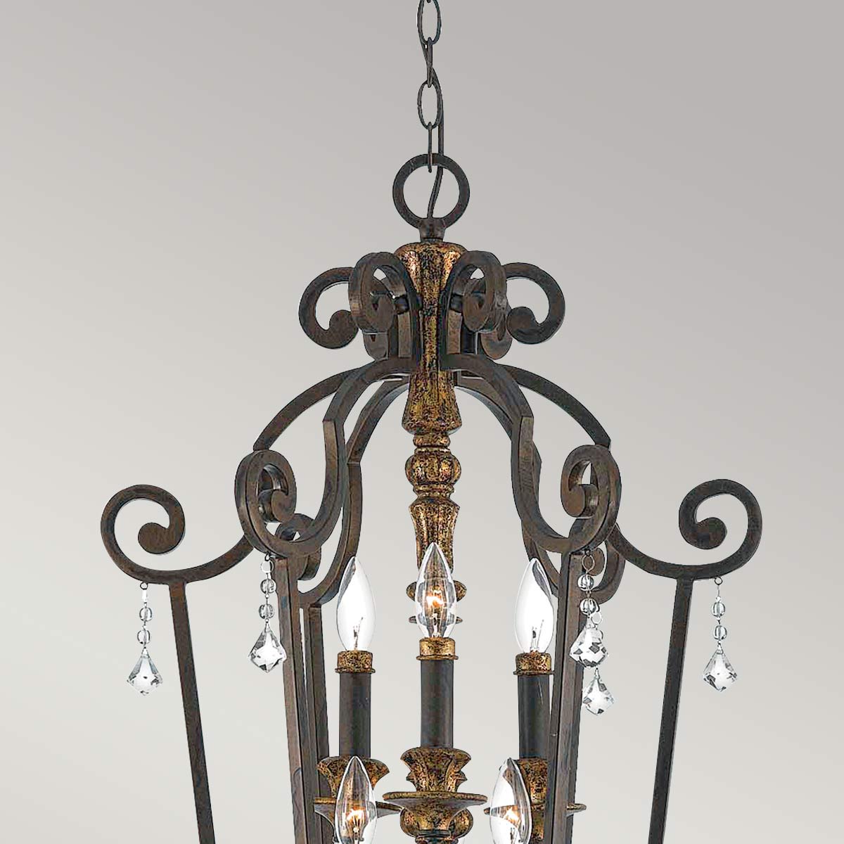 Détail du sommet avec chaîne, volutes en fer doré et cristaux taillés.