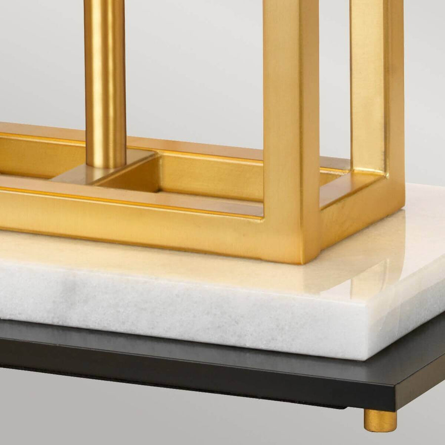 Détail de la base empilant marbre blanc, socle noir et petits pieds dorés.