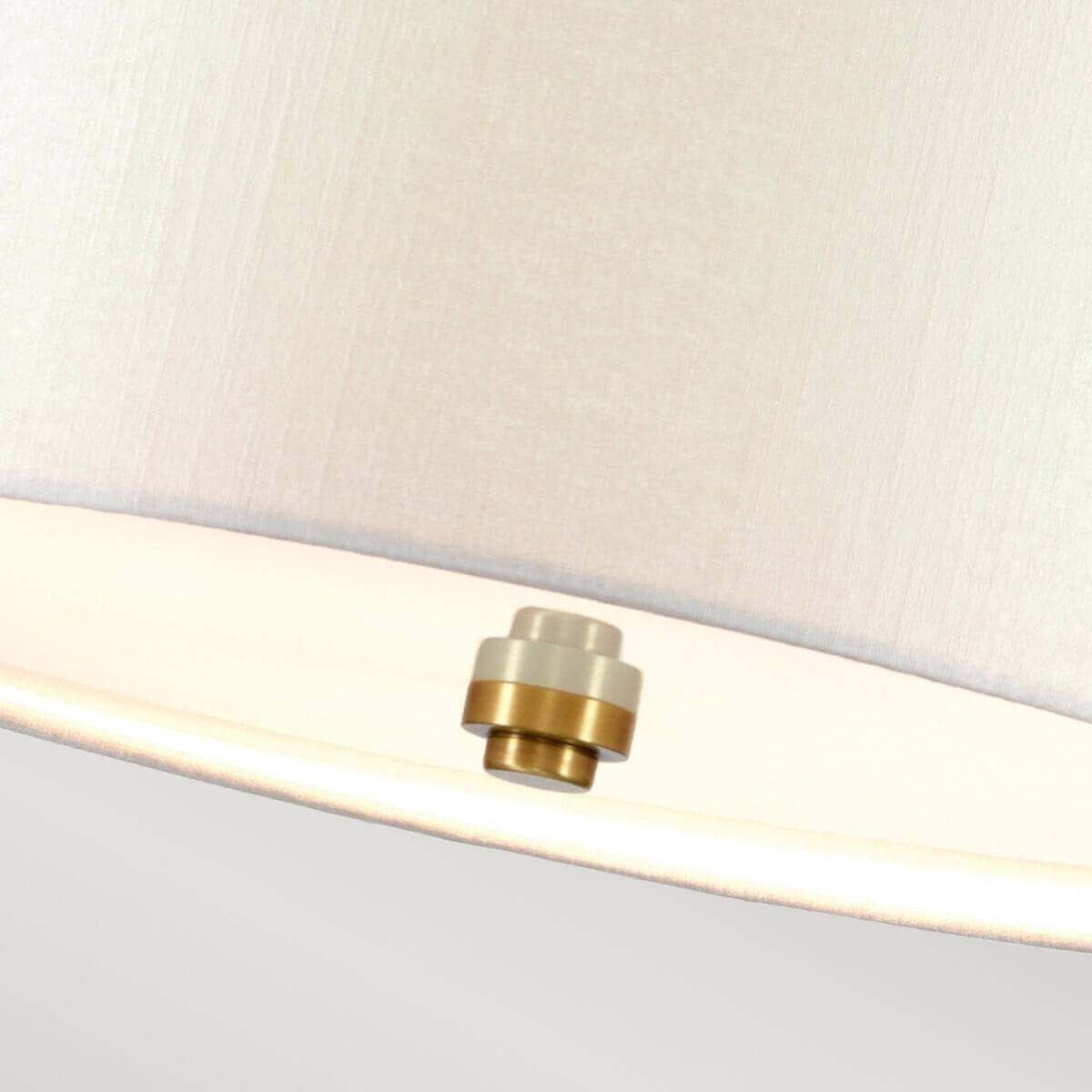 Détail du cabochon central en laiton sous l'abat-jour crème de la suspension