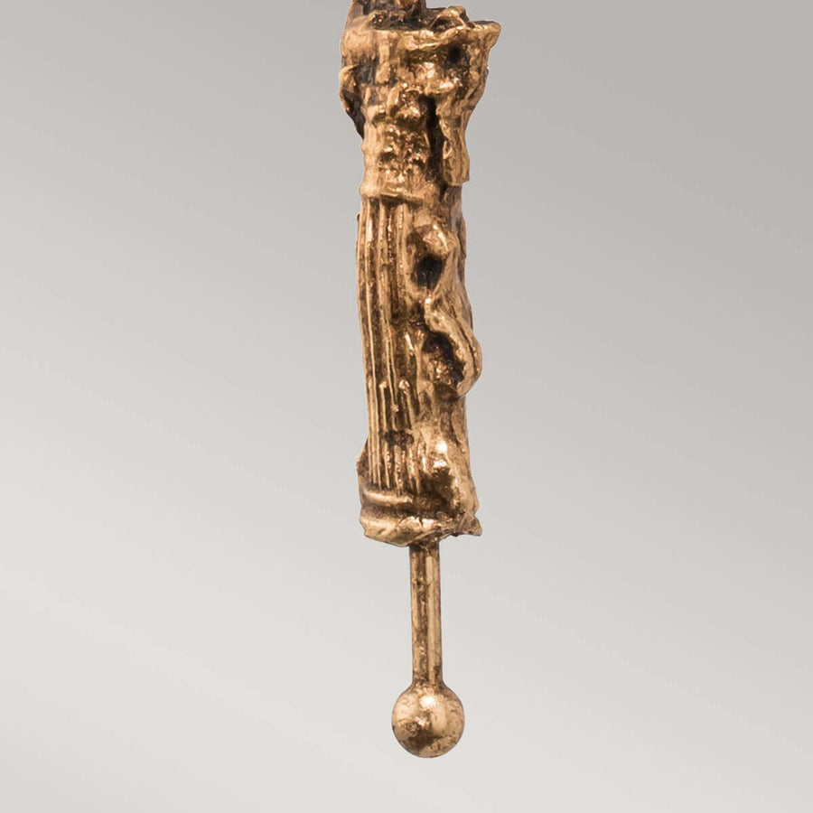 Détail du bas de l'applique, figure drapée dorée et petite sphère terminale