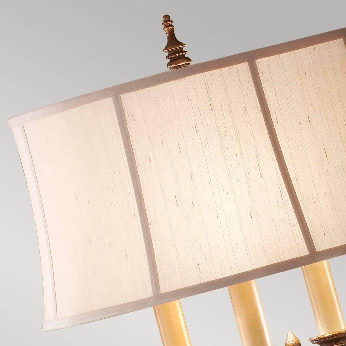 Gros plan sur le sommet de l'abat-jour en lin texturé et son fleuron ornemental doré