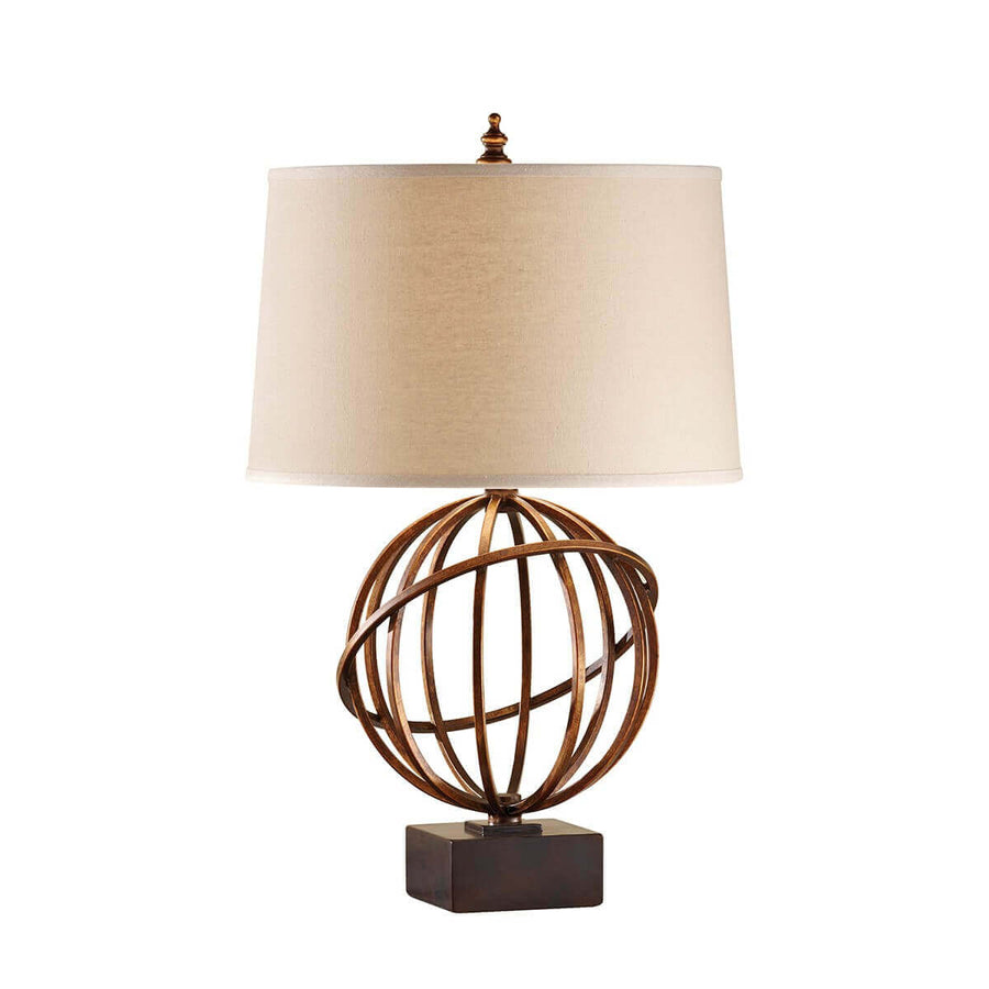 Lampe à poser dorée sur fond blanc, abat-jour beige et base sphérique ajourée.
