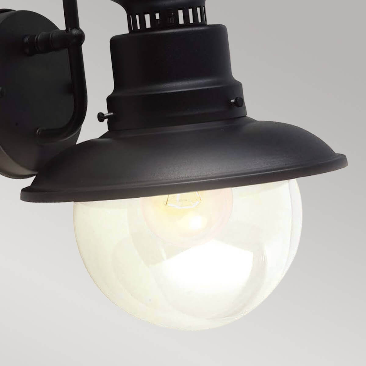 Détail rapproché du globe en verre éclairé, ampoule visible sous l'abat-jour noir