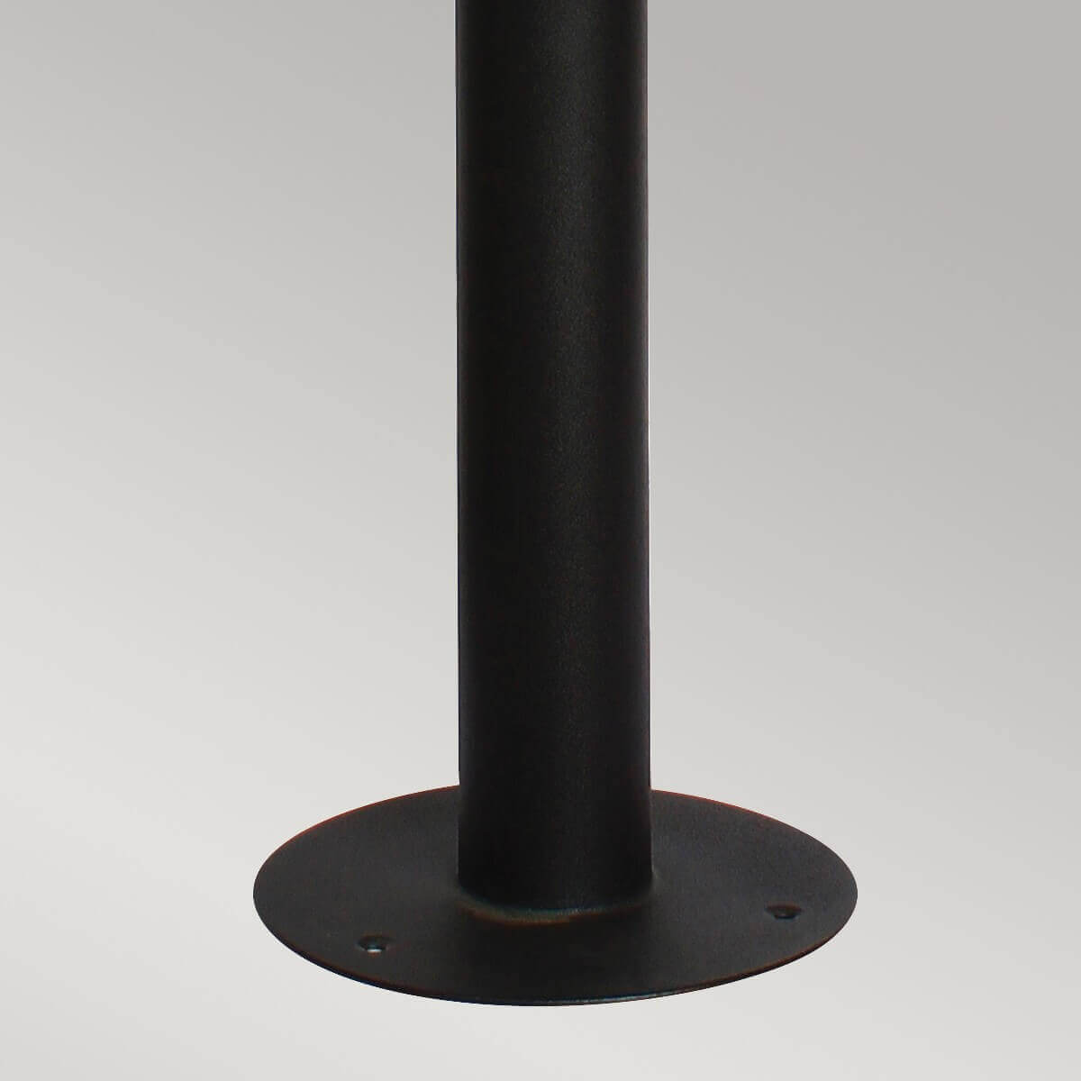 Détail de la base circulaire noire avec trous de fixation et fût vertical.