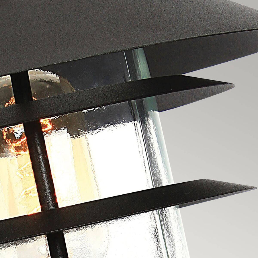 Détail rapproché des lamelles noires et du verre texturé autour de l'ampoule