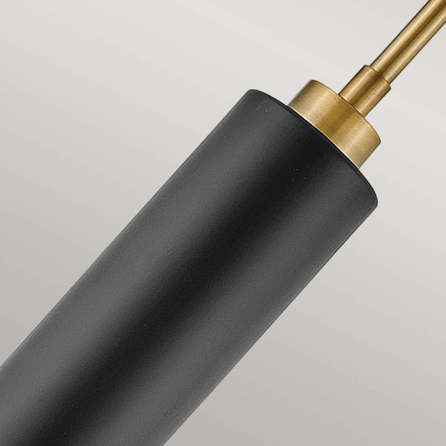 Détail du raccord en laiton brossé sur le corps cylindrique noir mat.