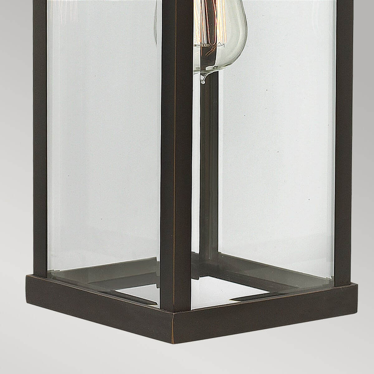 Détail de la base carrée et des panneaux de verre transparent du luminaire.