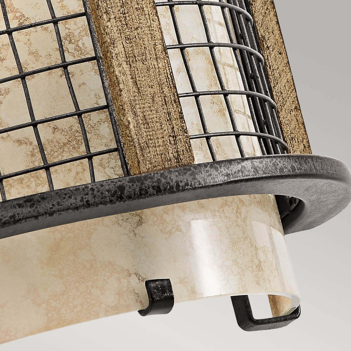 Vue rapprochée du bas : verre crème, grille, cerclage métallique et patte de fixation.
