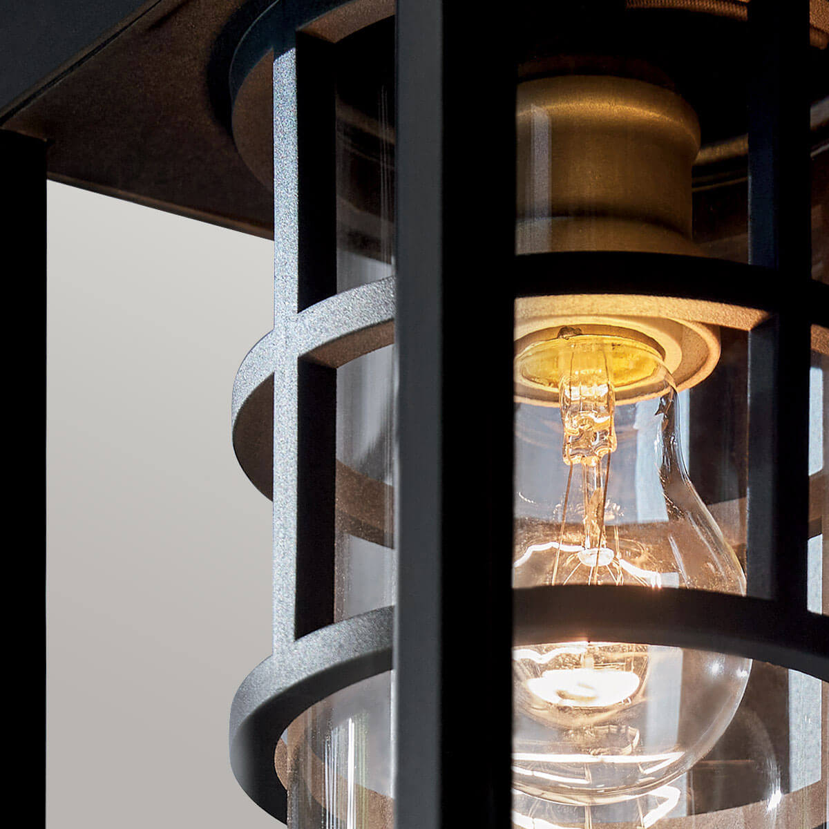 Gros plan sur l'ampoule dorée et la douille laiton sous le verre transparent