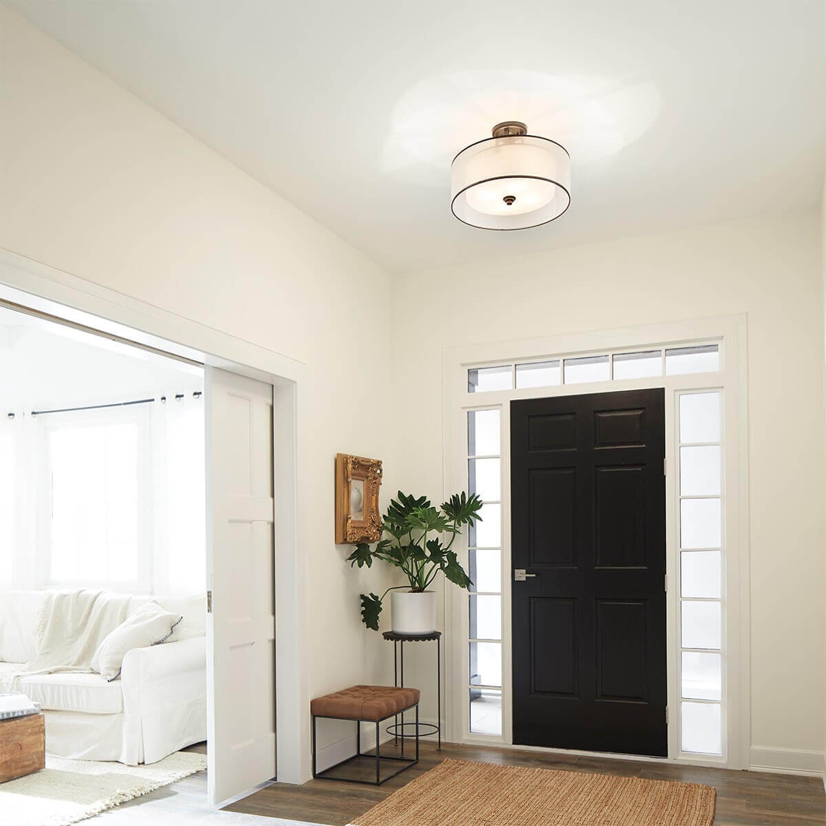 Mise en ambiance dans une entrée claire avec porte noire et mobilier discret