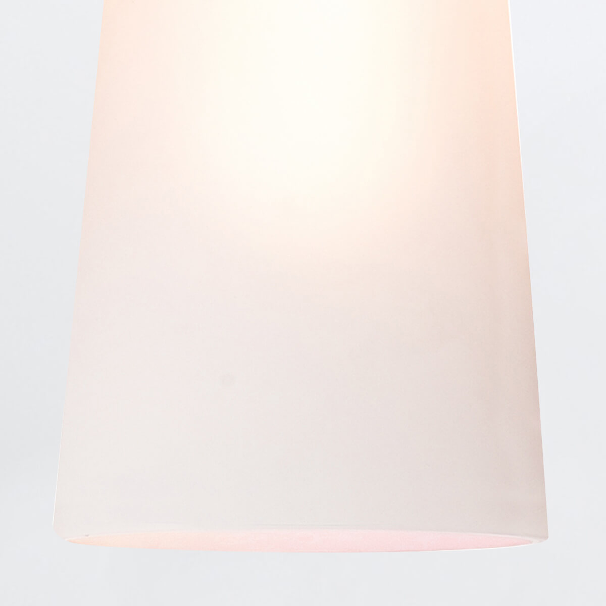Vue rapprochée du diffuseur en verre opale illuminé, laissant voir une lumière chaude.
