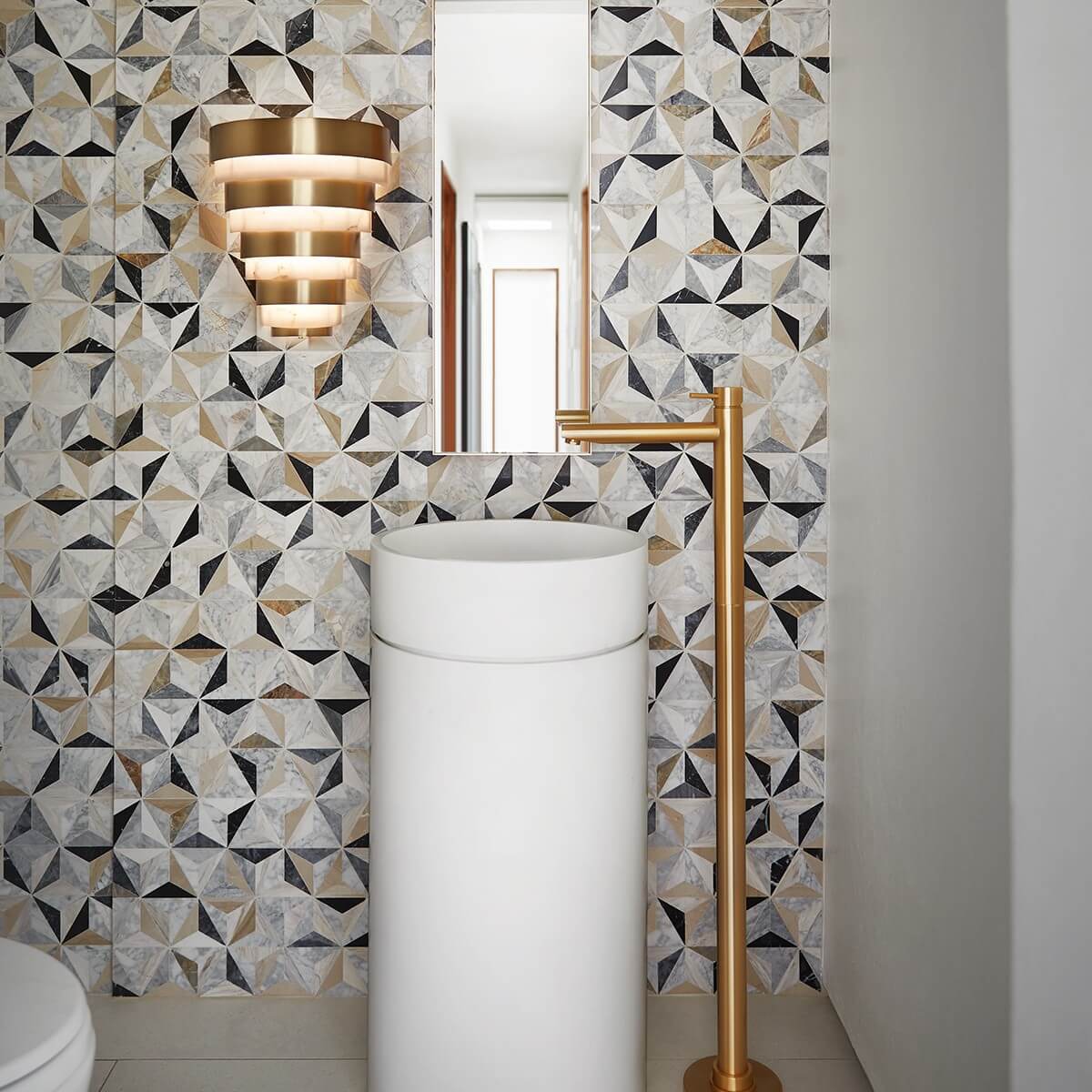 Mise en ambiance salle de bain, applique allumée au-dessus d'une vasque blanche