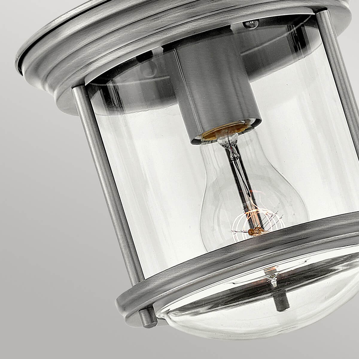 Gros plan sur l'ampoule à filament visible à travers le verre clair du luminaire