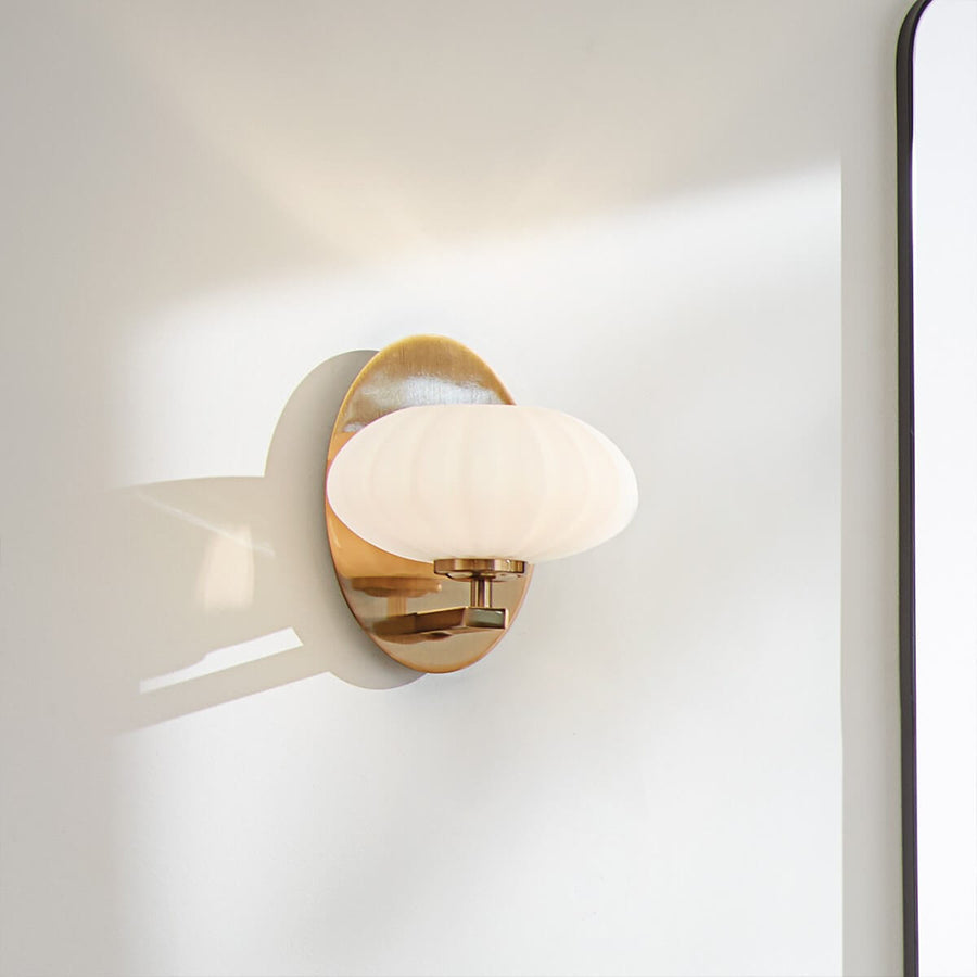 Applique allumée projetant une ombre douce sur le mur blanc.
