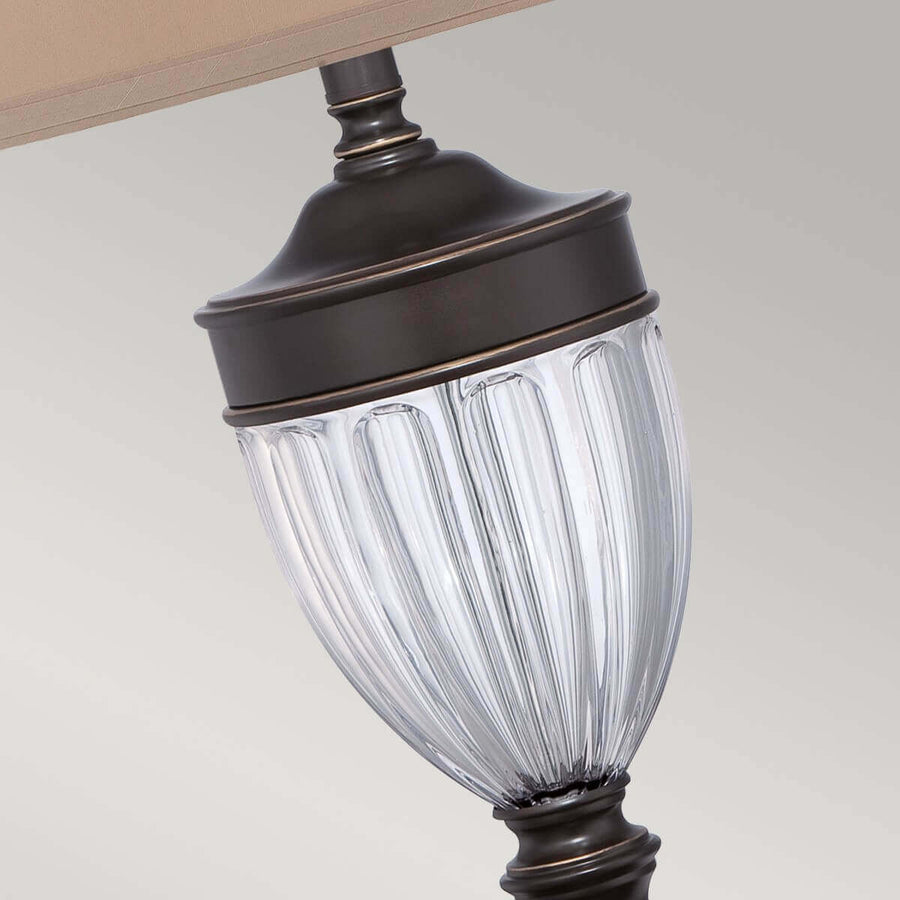 Détail du verre strié transparent et de la monture bronze de la lampe.