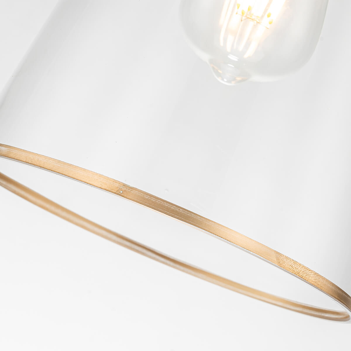 Gros plan sur le bord inférieur du verre transparent avec liseré doré et ampoule allumée.