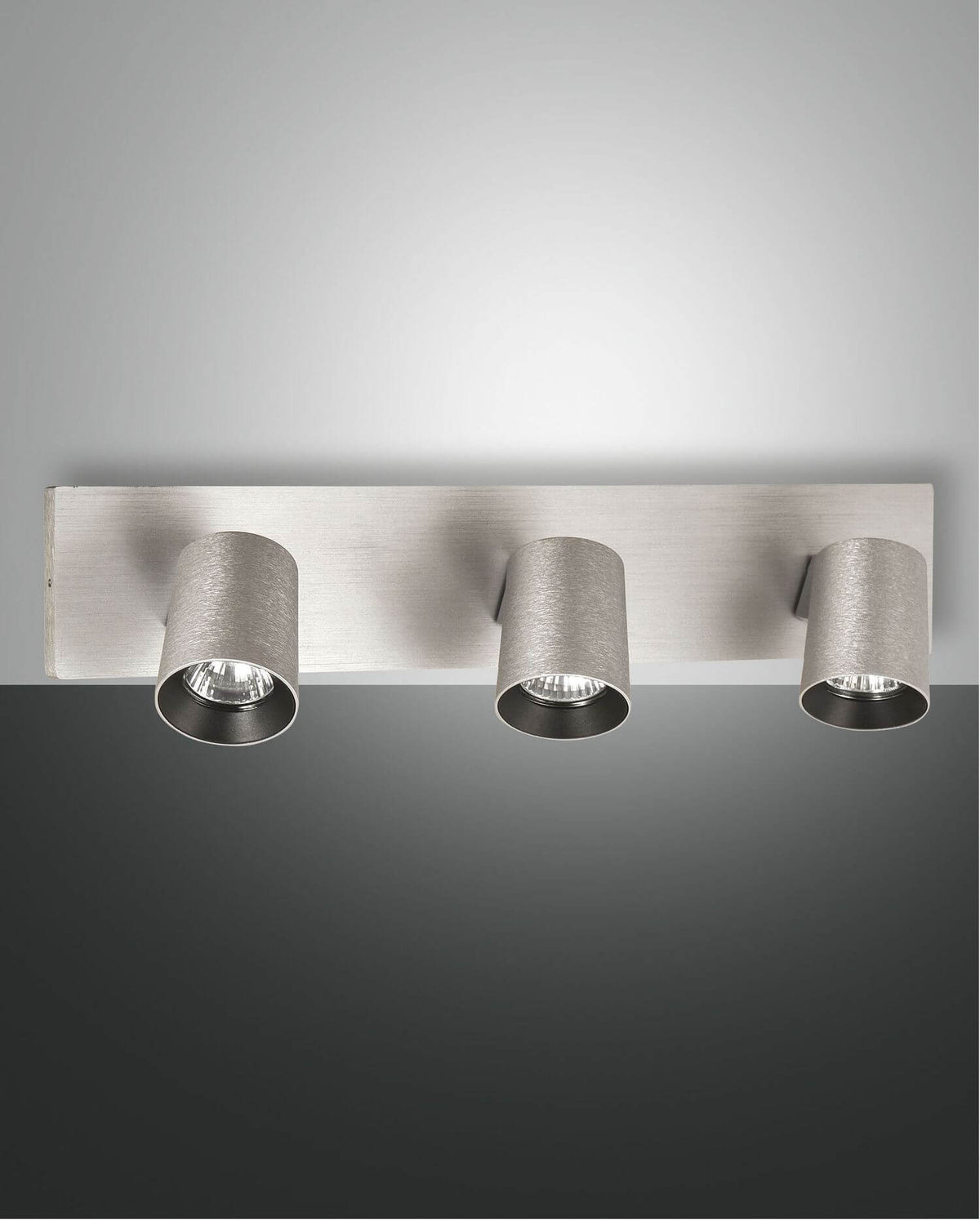 Vue de face du spot trois lumières en aluminium brossé avec projecteurs cylindriques orientables.