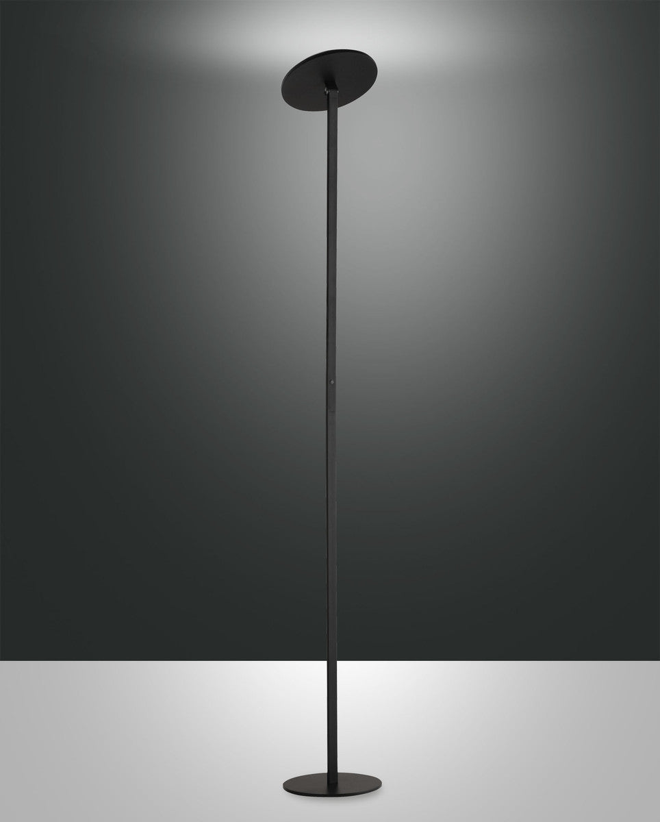 Lampadaire noir de face sur fond gris, tige fine et disque diffuseur orienté vers le haut
