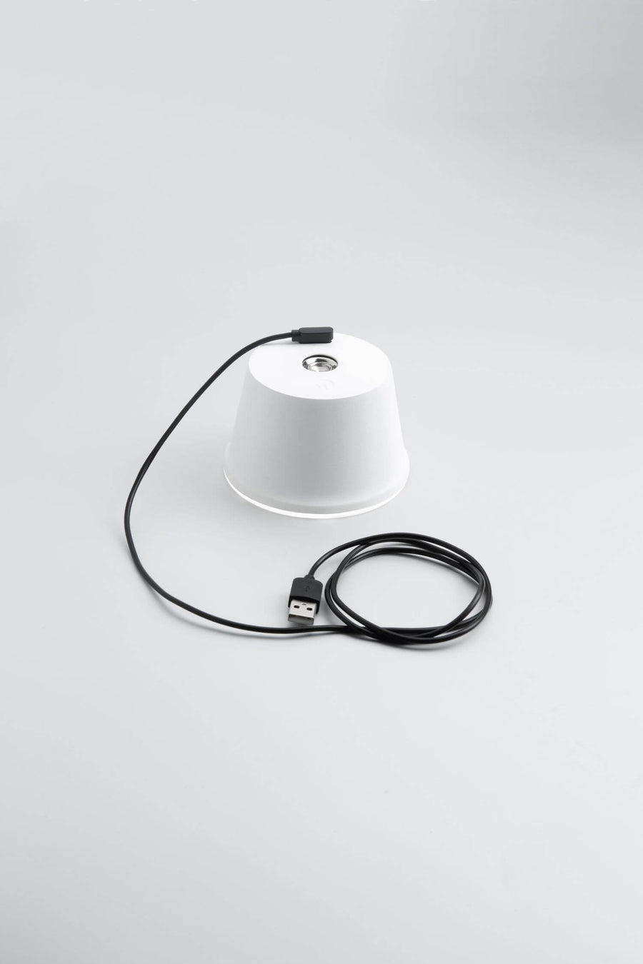 Lampe blanche posée retournée avec câble USB et connecteur, vue du dessus.